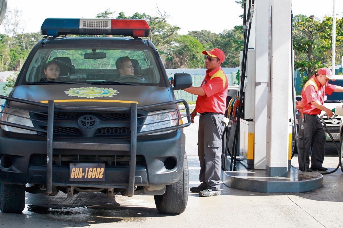 agentes de la Policía abastecen de combustible un vehículo de esa institución en el bulevar El Naranjo, Mixco. Se informó que solo reciben tres galones diarios.