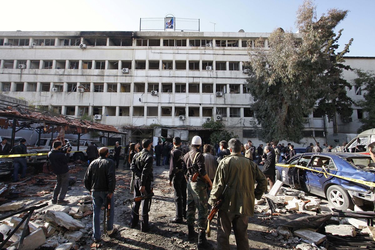 Personas permanecen en el sitio de un atentado con bomba en un edificio en Damasco, Siria, el 23 de diciembre de 2011. (Foto: AP)