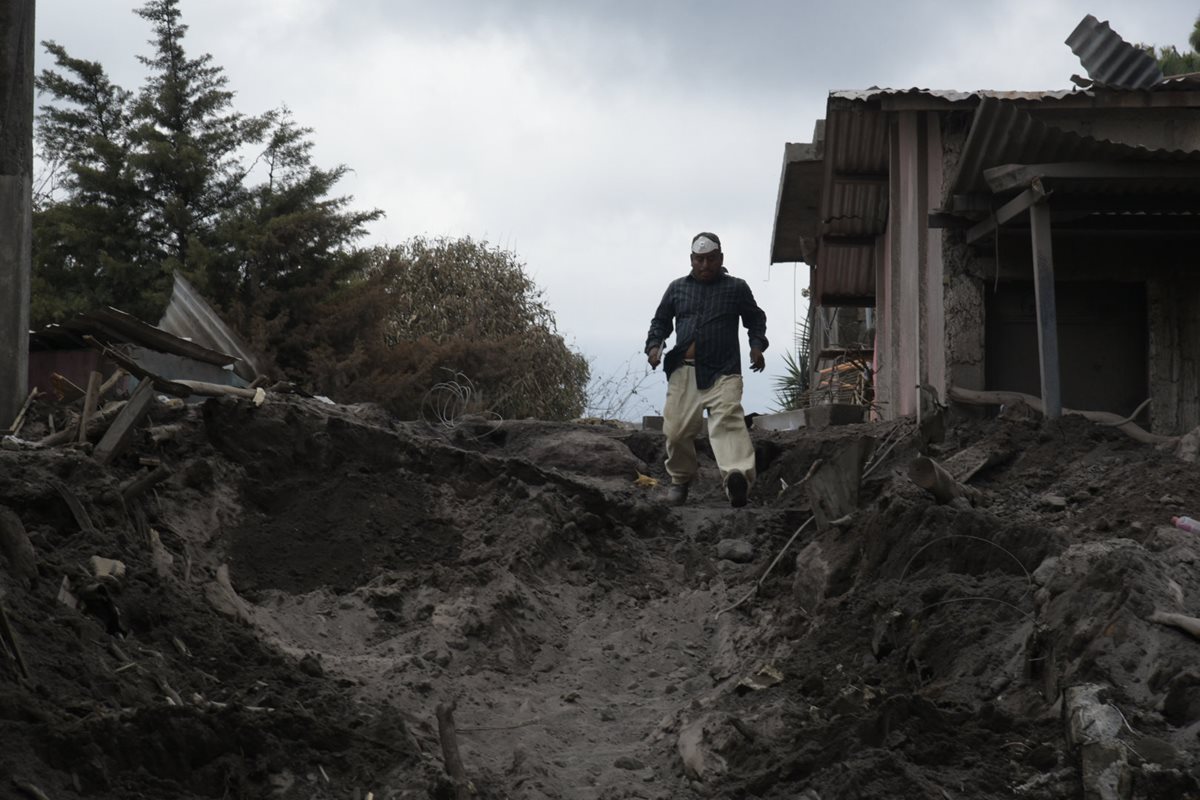 Un residente camina entre los escombros en la población de El Rodeo, la cual aún permanece sepultada tras la erupción del Volcán de Fuego. (Foto Prensa Libre: EFE)