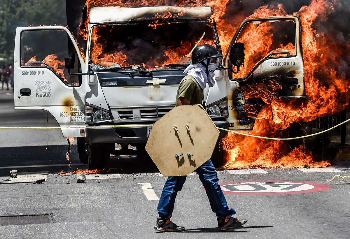 Un camión fue encendido por opositores que bloquea una avenida en Caracas. (AFP).