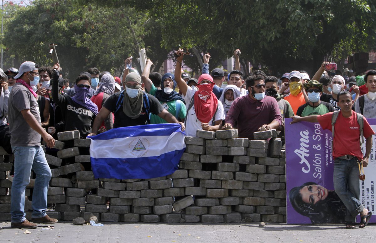 Un joven colocó una bandera de Nicaragua sobre una barricada de adoquines durante el cuarto día de protestas en Managua, Nicaragua. (Foto Prensa Libre: EFE)