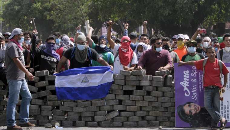Un joven colocó una bandera de Nicaragua sobre una barricada de adoquines durante el cuarto día de protestas en Managua, Nicaragua. (Foto Prensa Libre: EFE)