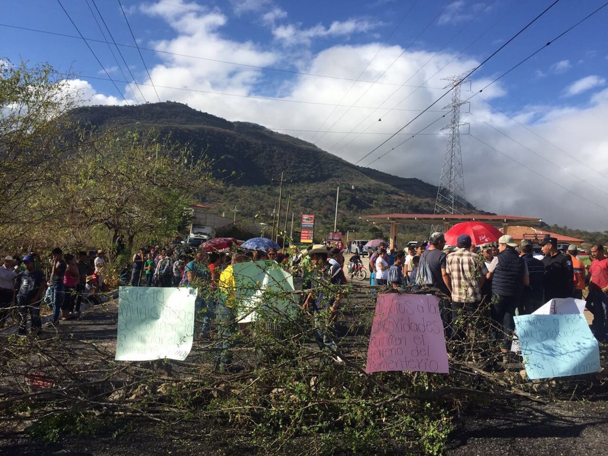 Hombres y mujeres sostienen carteles en rechazo a lo que consideran la privatización del cementerio. (Foto Prensa Libre: Mario Morales)