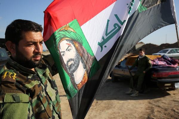 Un integrante de la milicia chií sostiene una bandera iraquí con la imagen del imán Hussein, nieto del profeta Mahoma, en las afueras de Kirkuk, Irak.(Foto Prensa Libre:AP)
