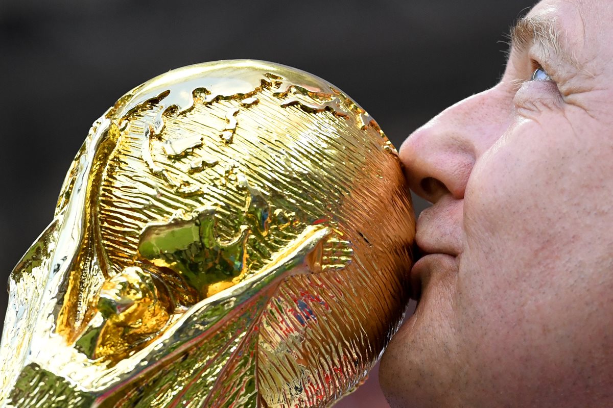 Un aficionado besa una réplica de la Copa del Mundo.