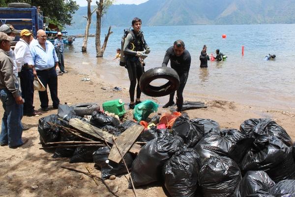 Miembros de la Escuela Panadivers extraen basura que vecinos y turistas han  lanzado al agua. (Foto Prensa Libre: Oswaldo Cardona)