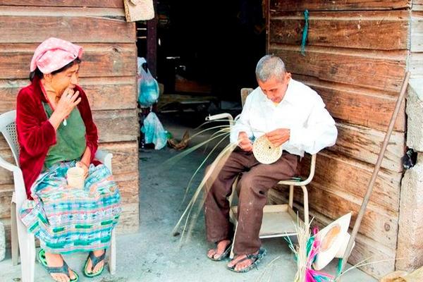 Juan Chen dialoga con su esposa, Pedrina,  en su vivienda de madera en la comunidad Pacux,  Rabinal, Baja Verapaz, mientras teje artículos de palma. (Foto Prensa Libre: Carlos Grave)