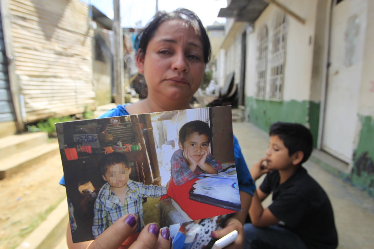 Elisia Higueros muestra fotografías en las que aparece su sobrino Jimmy Vega, de 8 años, en la casa que quedó soterrada por el deslizamiento. (Foto Prensa Libre: Edwin Bercián)
