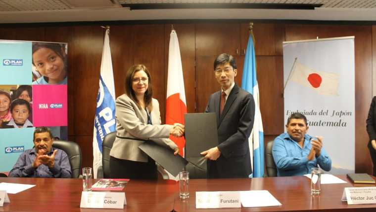 Débora Cóbar, directora de Plan Internacional, y Tomohiko Furutani, embajador del Japón, -al centro- luego de la firma del convenio de cooperación. (Foto Prensa Libre: Cortesía).