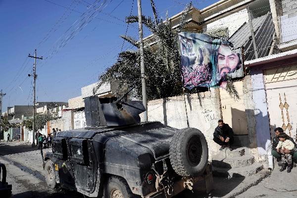 Una manta con el retrato del nieto de Mahoma, el imam Hussein, mientras pasa un vehículo militar iraquí. (Foto Prensa Libre: AFP)