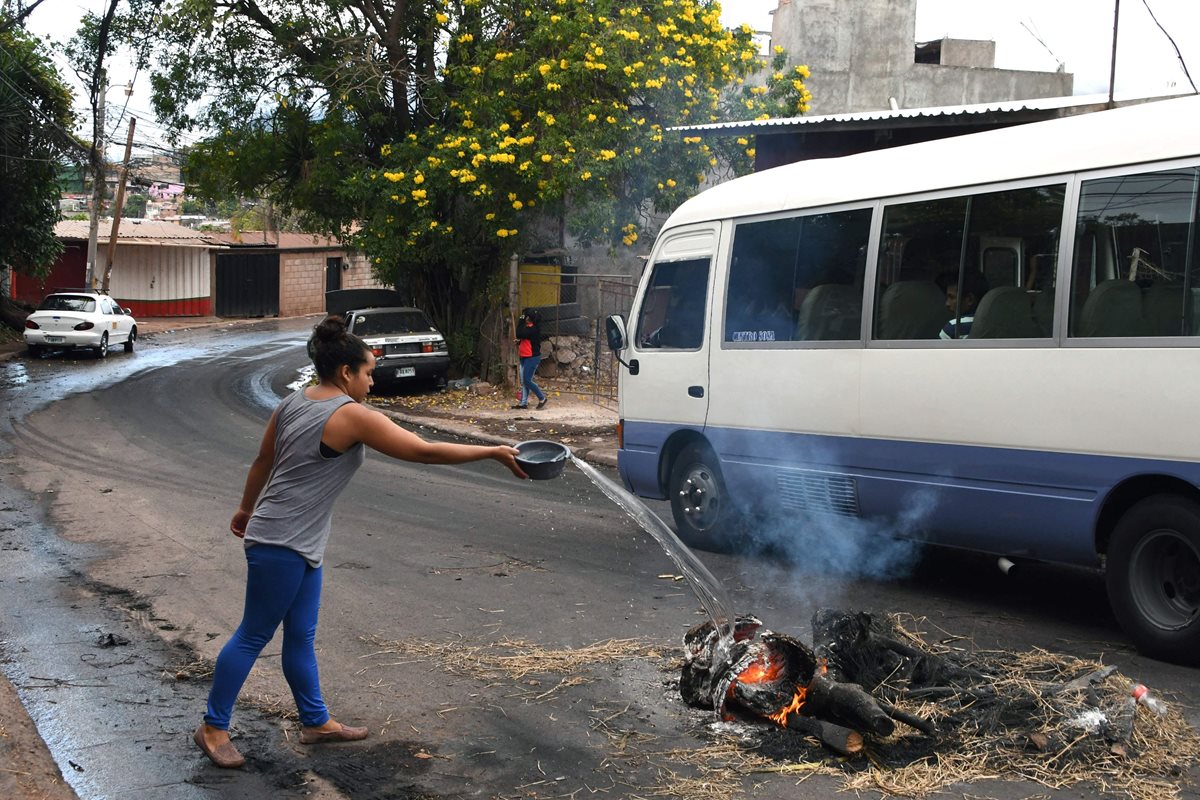 Una mujer intenta extinguir el fuego de una barricada establecida durante las protestas en Tegucigalpa, Honduras. (Foto Prensa Libre: AFP)