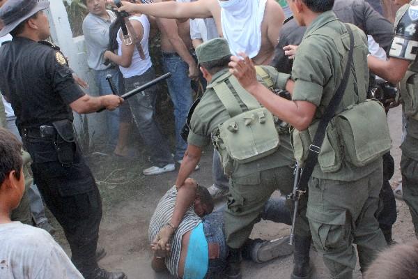 un Soldado sostiene a uno de los vapuleados.