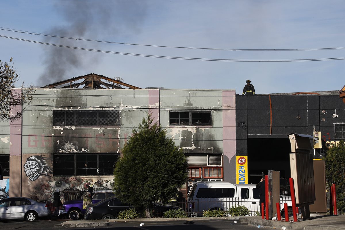 Un bombero observa la parte superior del edificio (aún humeante) donde murió la mayoría de víctimas. (Foto Prensa Libre: EFE).