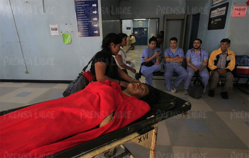 Olga Hernández lleva a su suegra Concepción Poc a la consulta externa ante la mirada de médicos que protestan porque se les pague su salario(Foto Prensa Libre: Edwin Bercían)