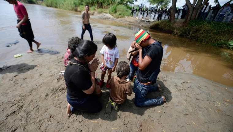 Una familia de migrantes hondureños ora en su trayecto hacia México y Estados Unidos. (Foto Prensa Libre: AFP)