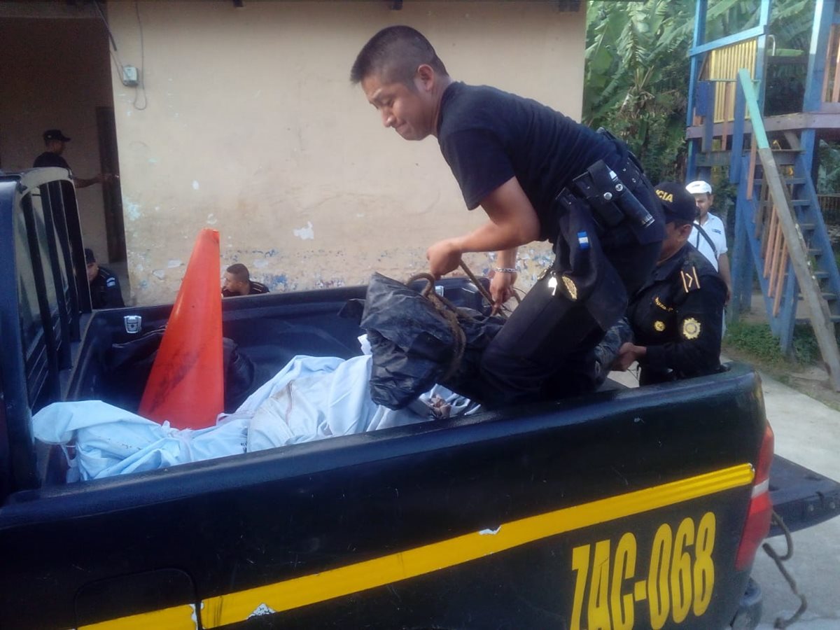 Agente de la Policía Nacional Civil ayuda con el traslado de los cuerpos de las víctimas hacia la morgue del Inacif en Zacapa. (Foto Prensa Libre: Mario Morales)