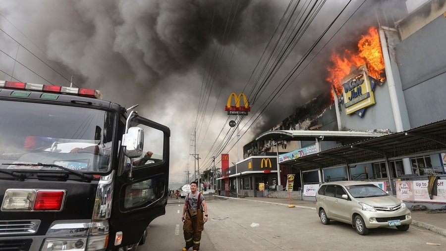 Bomberos intentan apagar un incendio en un centro comercial de cuatro niveles en filipinas. (Foto Prensa Libre: AFP)