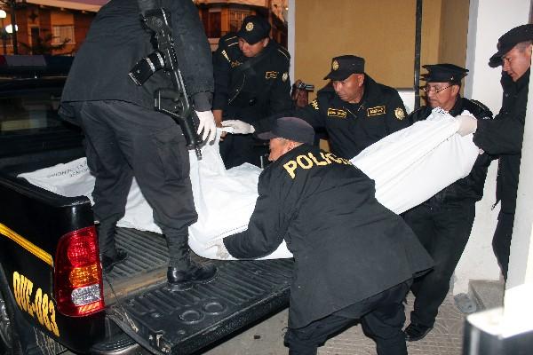 Agentes de la PNC suben en la palangana de un autopatrulla a uno de sus compañeros asesinados en junio del 2013, en la estación de Salcajá.
