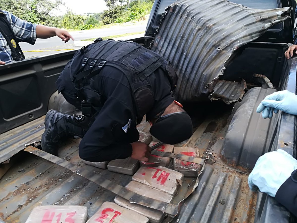 Un agente antinarcóticos extrae del doble fondo de la palangana del picop interceptado en la ruta interamericana, los paquetes con cocaína. (Foto Prensa Libre: Policía Nacional Civil)