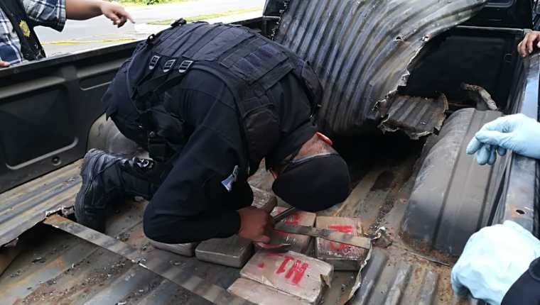 Un agente antinarcóticos extrae del doble fondo de la palangana del picop interceptado en la ruta interamericana, los paquetes con cocaína. (Foto Prensa Libre: Policía Nacional Civil)