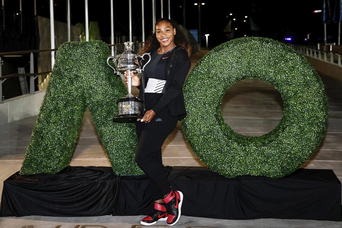 La tenista estadounidense Serena Williams posa y sonríe con el trofeo del Australia Open obtenido el fin de semana frente a su hermana Venus. (Foto Prensa Libre: EFE)