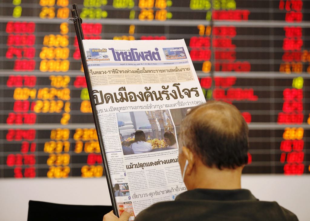 Un inversionistas ve el diario frente a indicadores de la bolsa de Tailandia. (Prensa Libre- EFE)