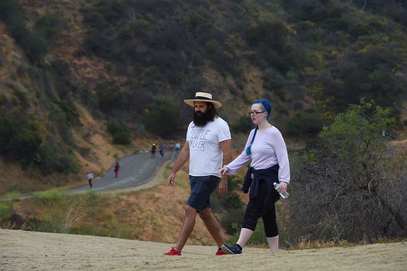 Chuck McCarthy y su cliente Anie Dee (D) caminan en Runyon Canyon Park, Los Angeles, el pasado 24 de mayo. (Foto Prensa Libre: AFP)