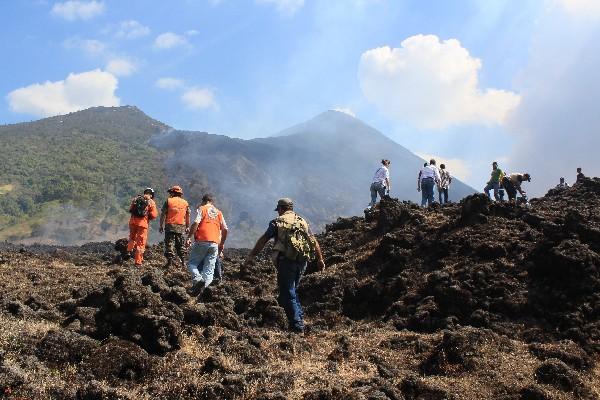 Personal de Conred asciende el Volcán de Pacaya. Al fondo se observan los daños por la lava.