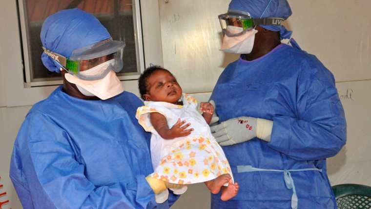 Enfermeros cargan a Nubia, una bebé que fue la última persona infectada con ébola en Guinea y que ya ha sanado. (Foto Prensa Libre: AFP).