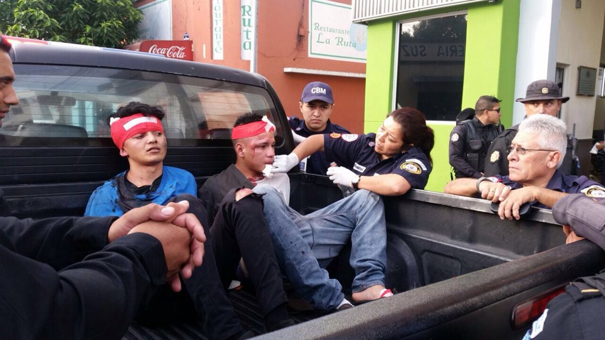 Los atacantes, bajo custodia policial, reciben atención de bomberos después de haber sido golpeados. (Foto Prensa Libre: Érick Ávila)