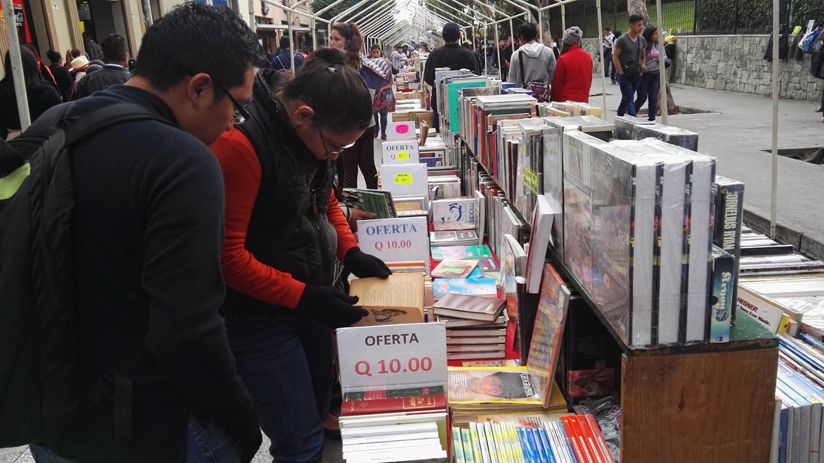 Dos personas observan los libros que se exhiben en el Paseo de la Sexta, zona 1. (Foto Prensa Libre: Edwin Pitán)