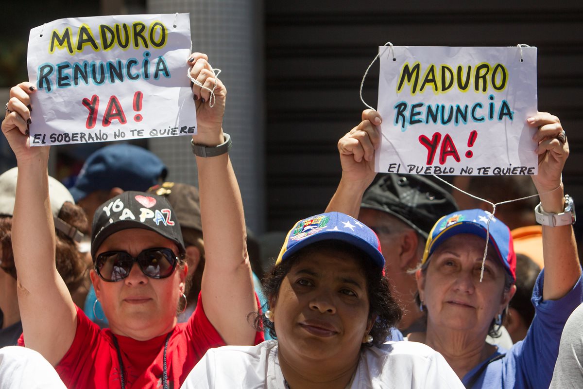 Mujeres sostienen pancartas en apoyo a que el presidente Nicolás Maduro abandone el poder. (Foto Prensa Libre: EFE).