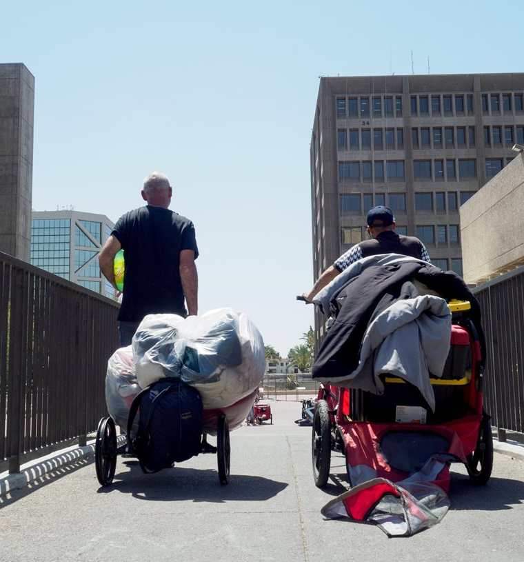 Dos hombres sin techo salen con un carrito con sus pertenencias en el Condado de Orange, California. (EFE).