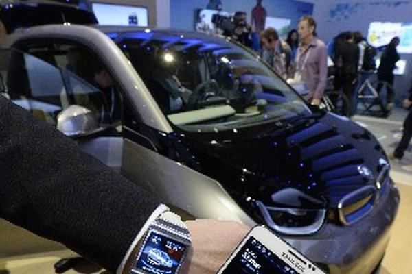 Un expositor muestra un teléfono y un reloj inteligente Samsung mientras estos interactúan con un vehículo eléctrico BMW 3i. (Foto Prensa Libre: EFE)