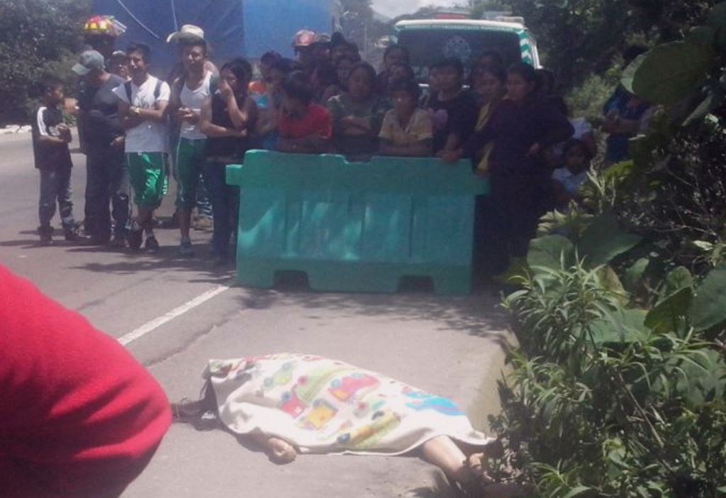 Vecinos observan el cadáver de la mujer que fue arrollada por un camión en el kilómetro 60 de la rua Interamericana. (Foto Prensa Libre: José Rosales)