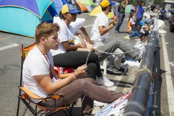 Los estudiantes venezolanos se encadenan en protesta a fallo judicial. (Foto Prensa Libre: AFP).