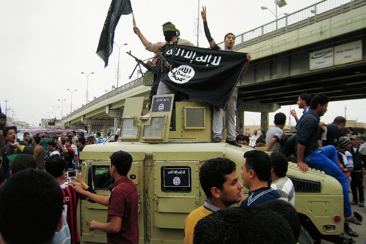 Combatientes del Estado Islámico ondean banderas en un vehículo militar iraquí en Faluya, Irak. (Foto Prensa LIbre:AP)