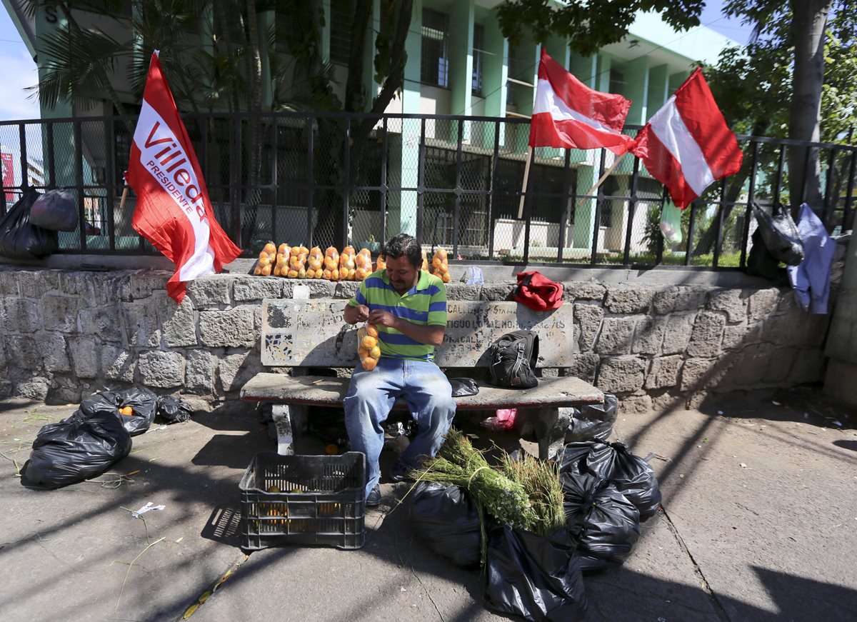 Un hombre vende sus frutas en la zona donde promocionan banderas de diferentes partidos políticos de Honduras en Tegucigalpa. (Foto Prensa Libre: EFE)