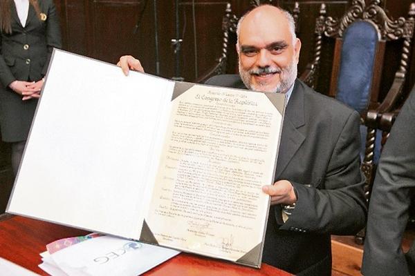 Sandino Asturias,  nieto del Premio Nobel,  muestra  una copia del decreto 17-2014. (Foto Prensa Libre: Esbin García)