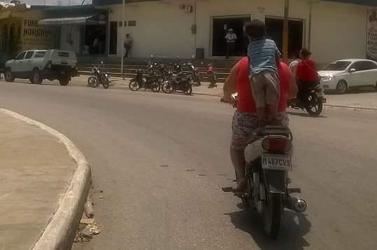Niño fotografiado en San Benito, Petén, es trasladado de pie y sin casco en motocicleta. (Foto Prensa Libre: Rigoberto Escobar)
