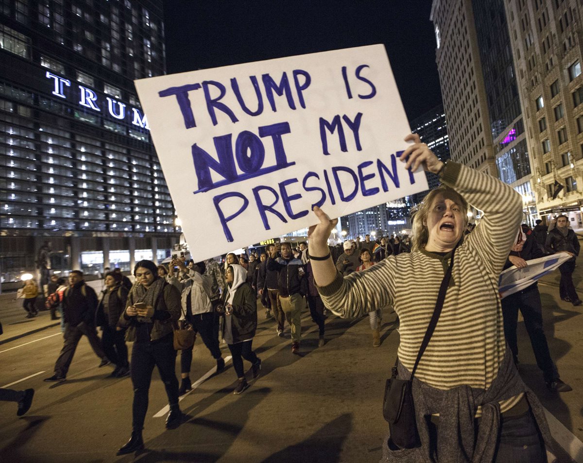 "Trump no es mi presidente" reza el cartel de una mujer que protesta afuera de la Torre Trump en Chicago. (Foto Prensa Libre: AFP)