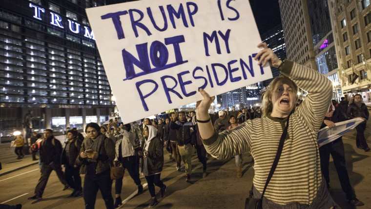 "Trump no es mi presidente" reza el cartel de una mujer que protesta afuera de la Torre Trump en Chicago. (Foto Prensa Libre: AFP)