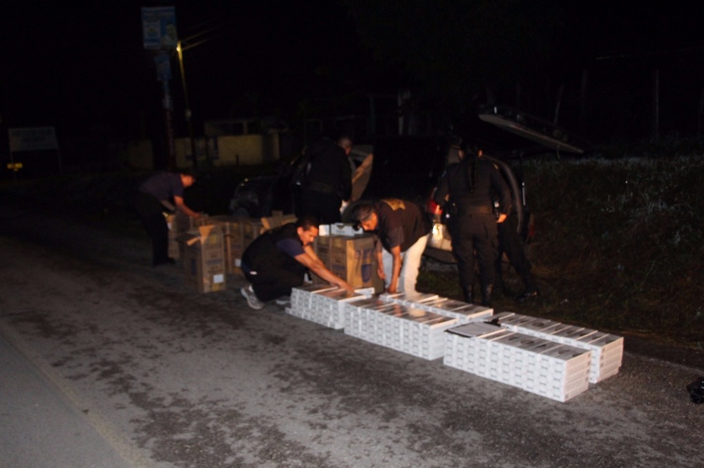 Investigadores contabilizan parte de los paquetes que contienen cigarrillos de contrabando, en Flores, Petén. (Foto Prensa Libre: PNC).