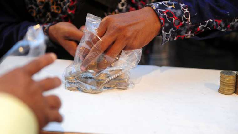 Una mujer intercambia monedas en Allahabad, India.(Foto Prensa Libre: AFP).