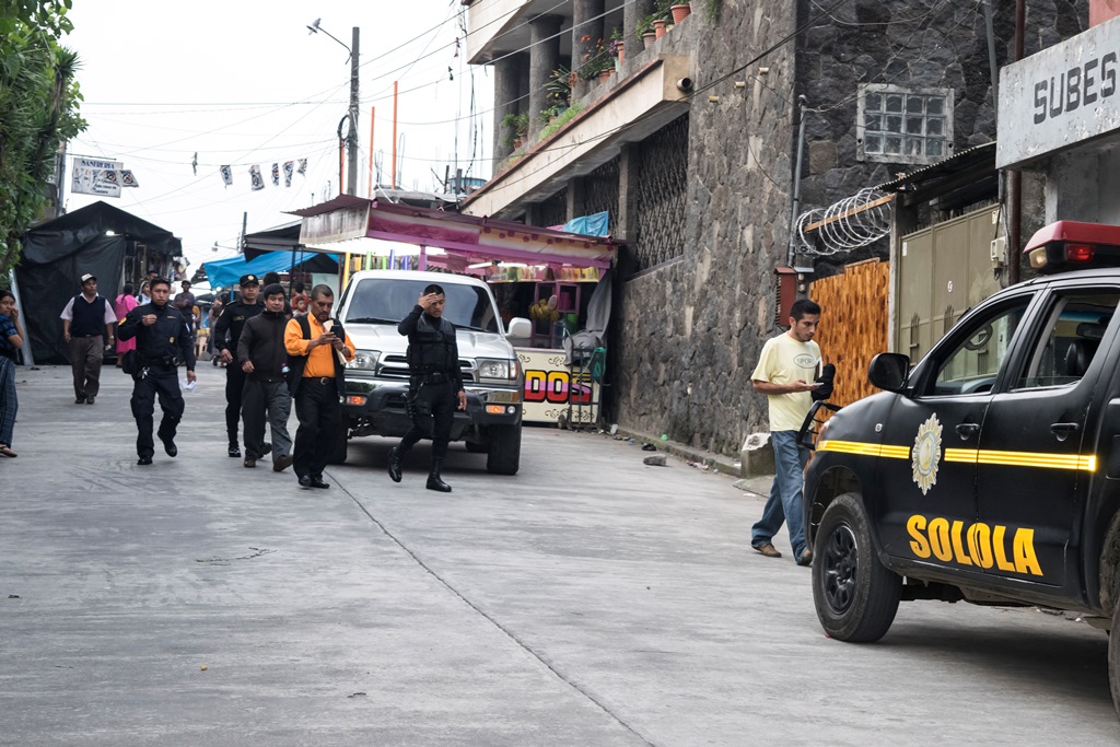 Agentes de la Policía Nacional Civil custodian a dos capturados de la comuna de San Lucas Tolimán, Sololá. (Foto: cortesía de José Cerezo)