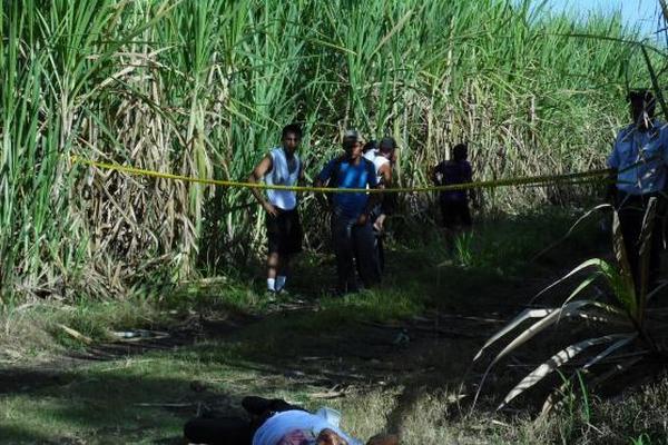 Curiosos observan el cadáver de Lester Eliseo Pelén, quien fue encontrado en Santa Lucía Cotzumalguapa. (Foto Prensa Libre: Enrique Paredes)