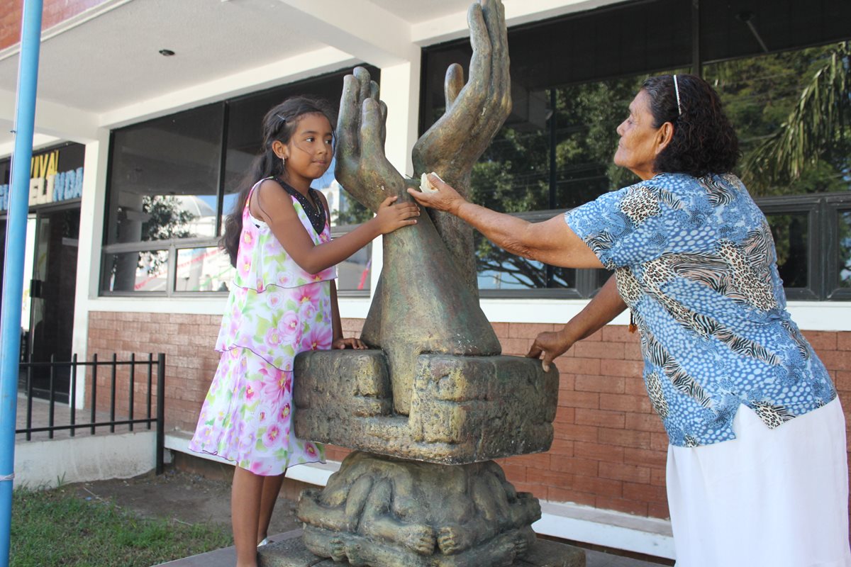 Ashly Ríos –izq- y Evangelina Gutiérrez colocan una rosa en el monumento a la Paz, en Jutiapa. (Foto Prensa Libre: Óscar Figueroa).