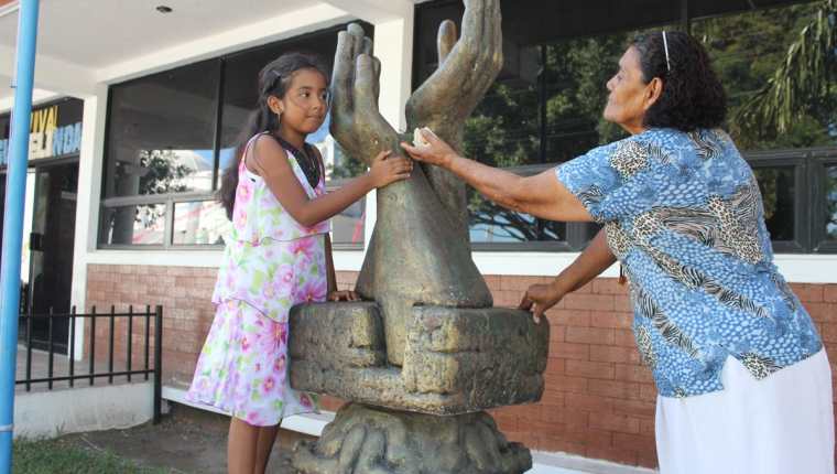 Ashly Ríos –izq- y Evangelina Gutiérrez colocan una rosa en el monumento a la Paz, en Jutiapa. (Foto Prensa Libre: Óscar Figueroa).