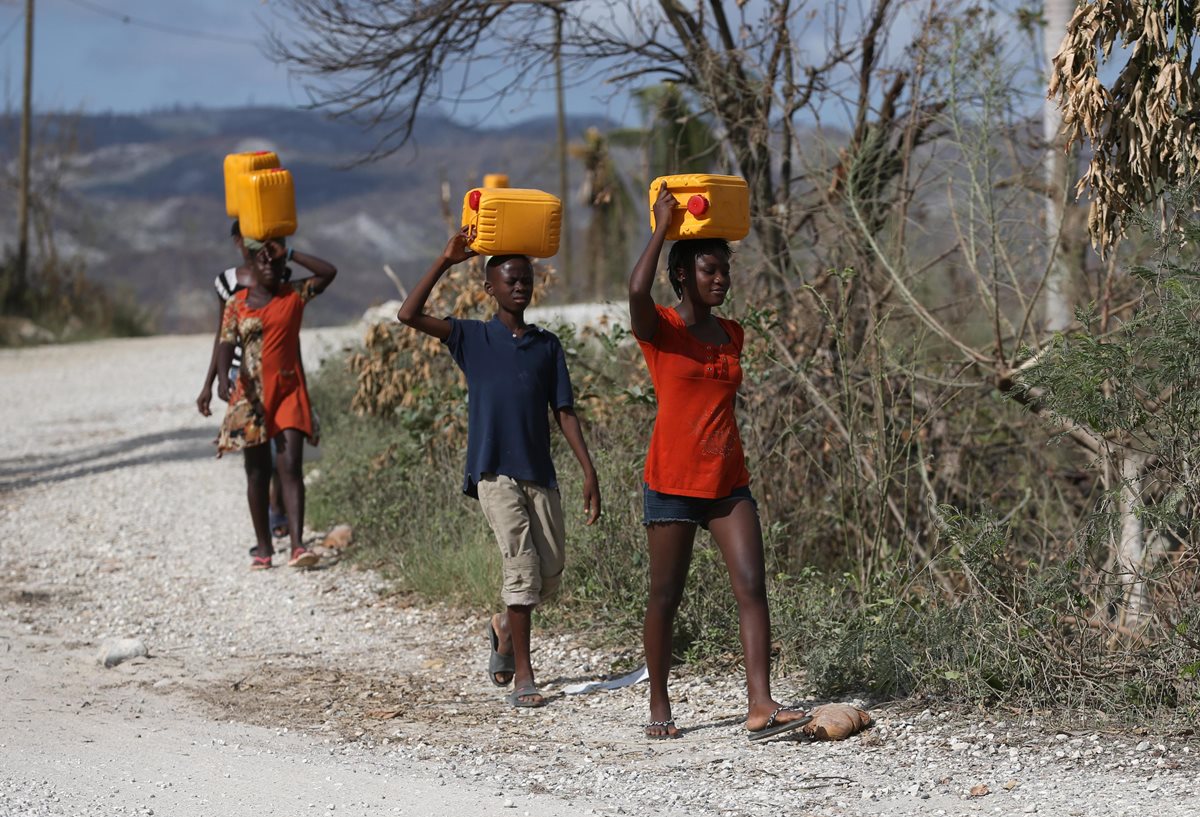 Mujeres transportan agua limpia en la devastada región de Jeremie, Haití. (Foto Prensa Libre: EFE).
