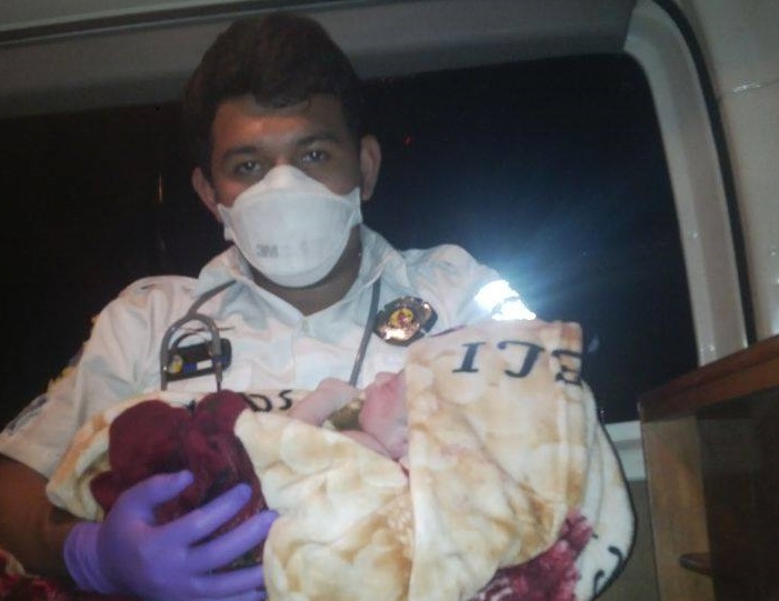 El socorrista Manuel Hernández sostiene al recién nacido dentro de la ambulancia en la que fue atendido el parto. (foto Prensa Libre: Jorge Tizol)